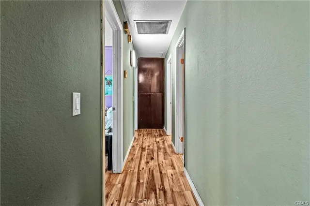 a view of a hallway with wooden floor and a bathroom