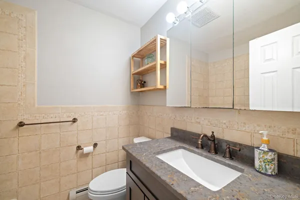 a bathroom with a granite countertop toilet sink and mirror