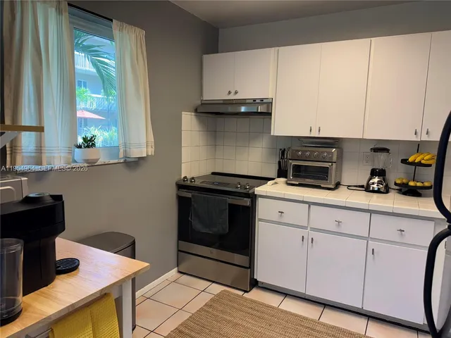 a kitchen with granite countertop white cabinets and black appliances