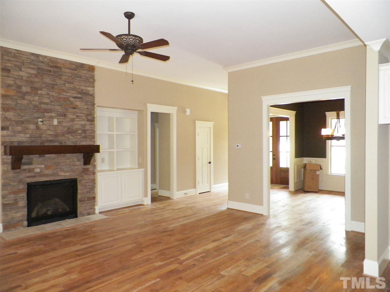 6128 Spring Branch Circle Raleigh, NC 27603 - Photo 9 of 25 a view of a livingroom with a fireplace a ceiling fan and wooden floor