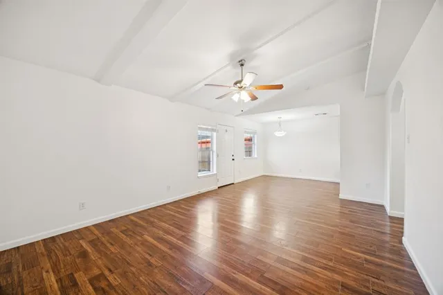 an empty room with wooden floor and ceiling fan