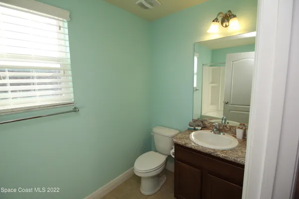 a bathroom with a granite countertop toilet sink and mirror