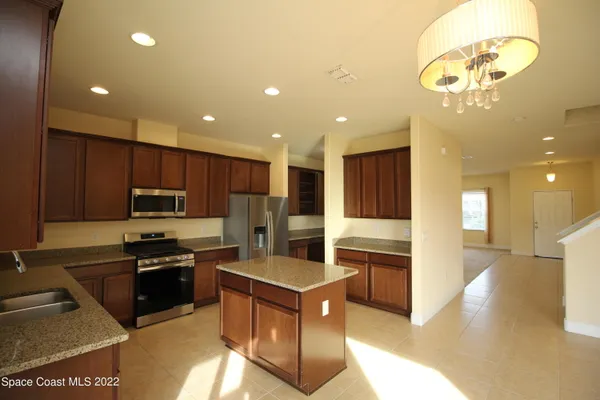 a kitchen with kitchen island granite countertop stainless steel appliances cabinets a sink and a counter top space