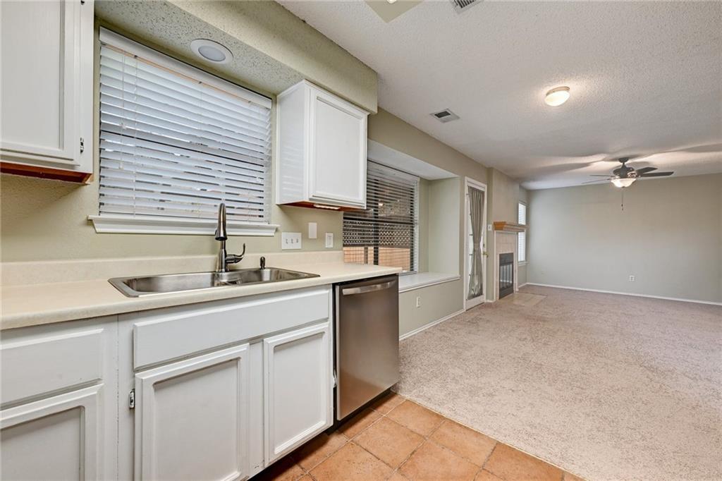 An open layout connects the tile-floored kitchen directly to a carpeted living space.