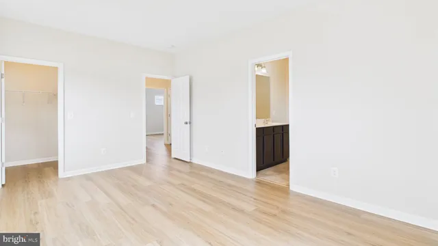 a view of an empty room with wooden floor and closet