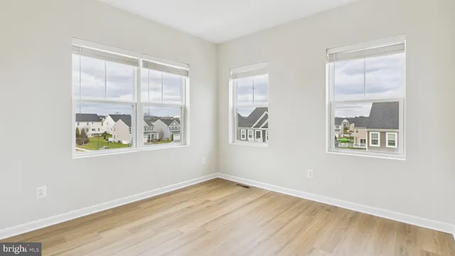 a view of an empty room with a window and wooden floor