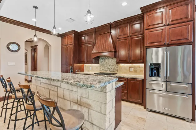 a kitchen with stainless steel appliances granite countertop a refrigerator a stove and a sink with cabinets