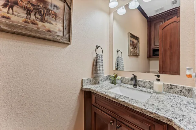 a bathroom with a granite countertop sink and a mirror