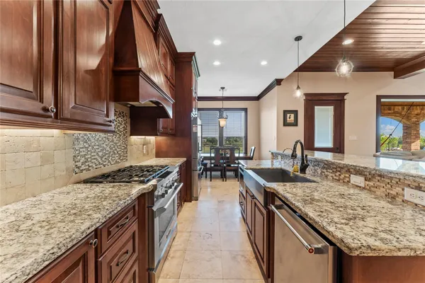 a kitchen with kitchen island granite countertop a stove and a sink
