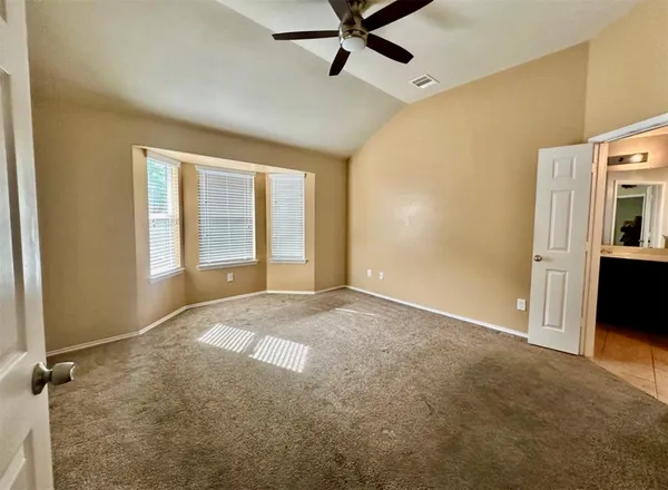a view of an empty room with a window and a kitchen