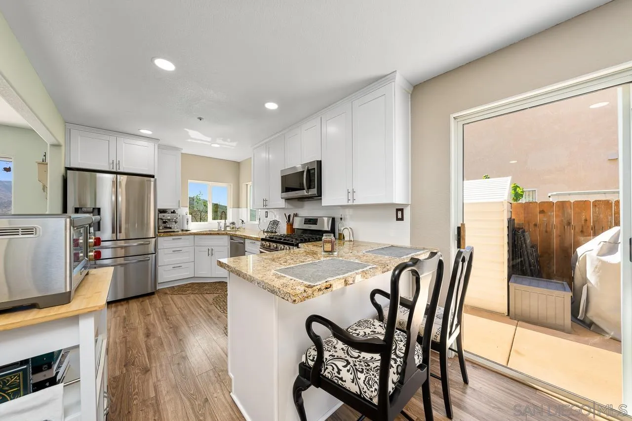 9851 Avenida Ricardo Spring Valley, CA 91977 - Photo 12 of 41 a kitchen with stainless steel appliances granite countertop a refrigerator a stove top oven a sink dishwasher and white cabinets with wooden floor