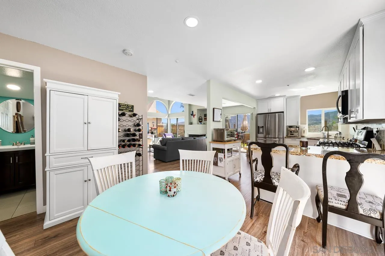 9851 Avenida Ricardo Spring Valley, CA 91977 - Photo 13 of 41 a kitchen with stainless steel appliances kitchen island granite countertop a refrigerator a stove a sink a dining table and chairs with wooden floor
