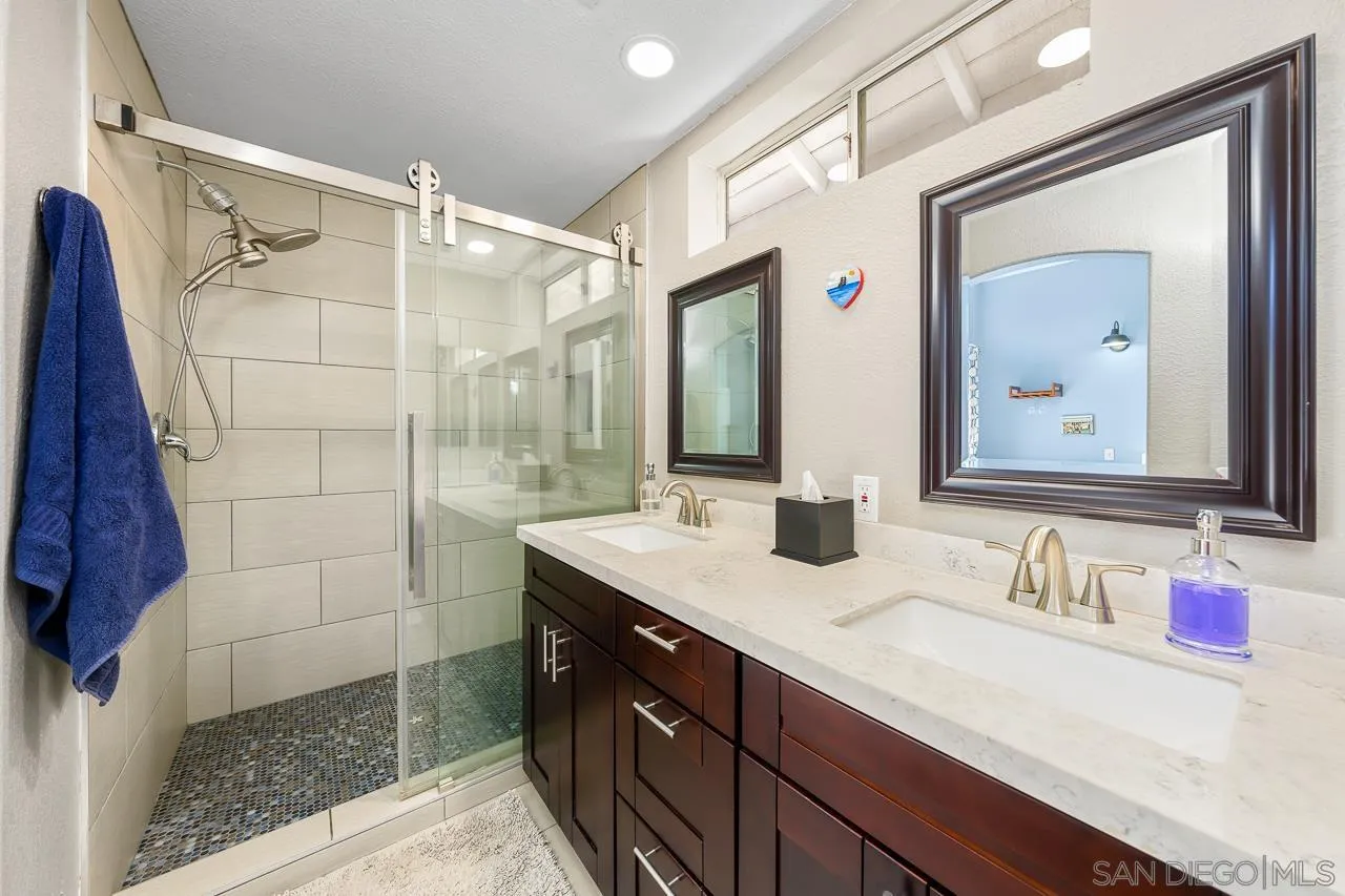 9851 Avenida Ricardo Spring Valley, CA 91977 - Photo 26 of 41 a bathroom with a granite countertop sink a mirror and shower