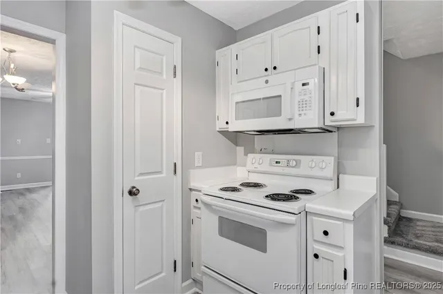 a kitchen with white cabinets and white appliances