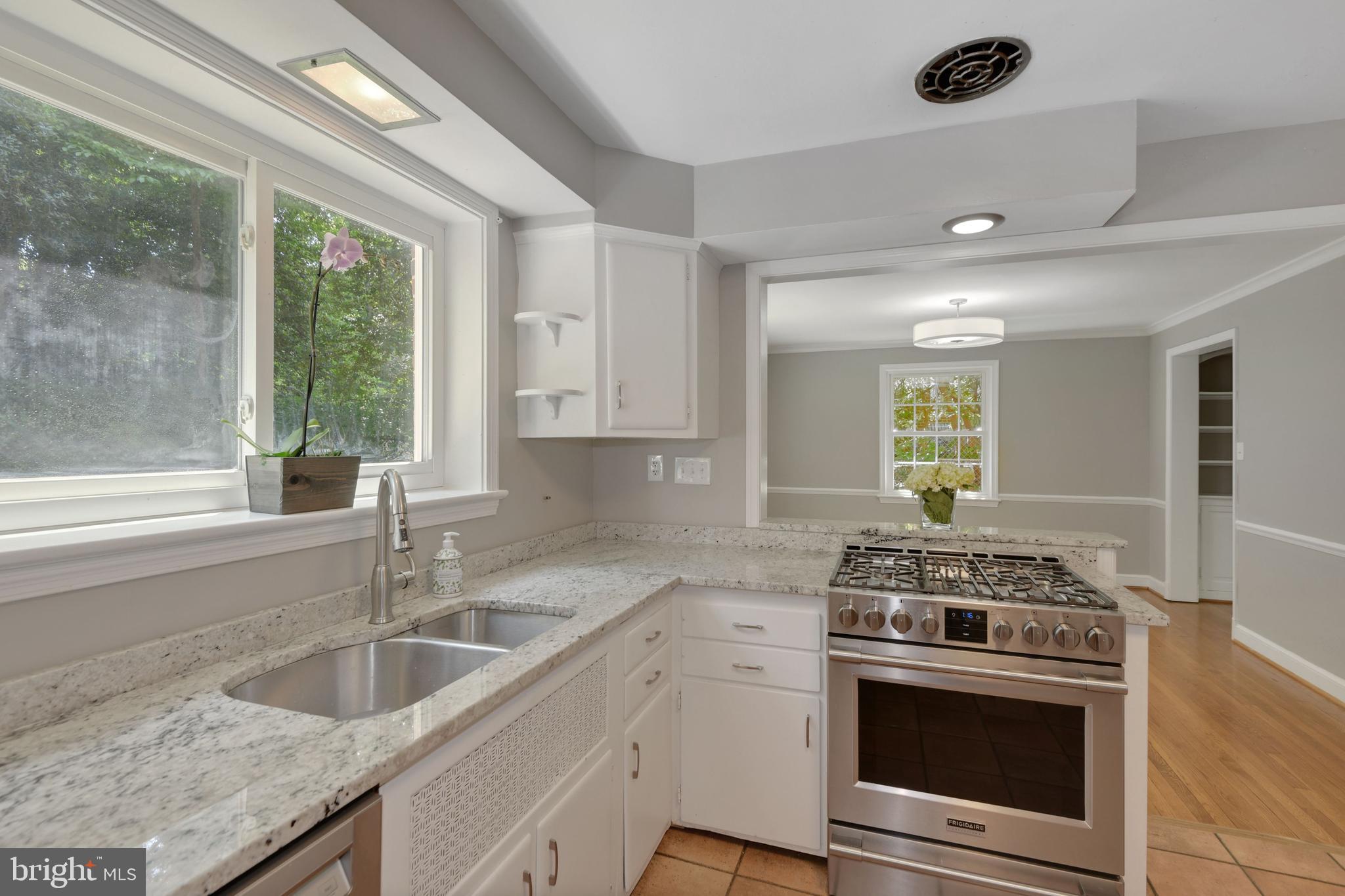 7215 Rollingwood Drive Chevy Chase, MD 20815 - Photo 12 of 42 a kitchen with granite countertop a sink stainless steel appliances a counter space and a window