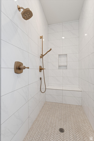 1192 East Corral Way Washington, UT 84780 - Photo 30 of 81 Walk-in shower featuring a herringbone tile floor, white marble-look wall tiles, bronze-finish fixtures, a built-in bench, and a recessed shower niche