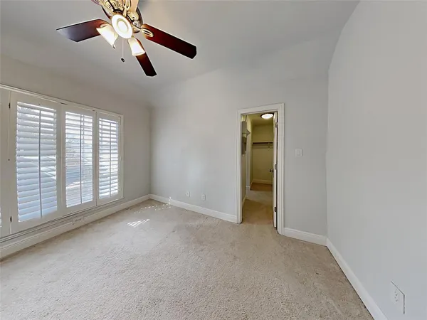 an empty room with chandelier fan and windows
