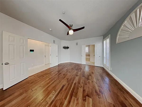 a view of empty room with wooden floor and ceiling fan