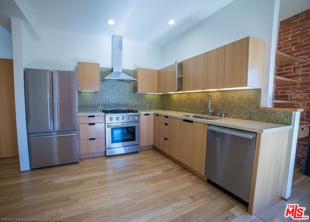 a kitchen with stainless steel appliances granite countertop a refrigerator a sink and a stove