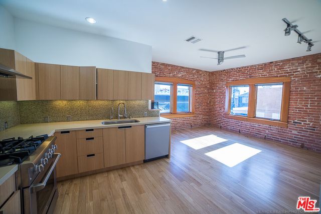 a kitchen with granite countertop a stove top oven a sink dishwasher and a dining table with wooden floor