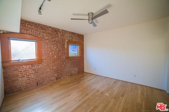 a view of a hallway with wooden floor and a bathroom