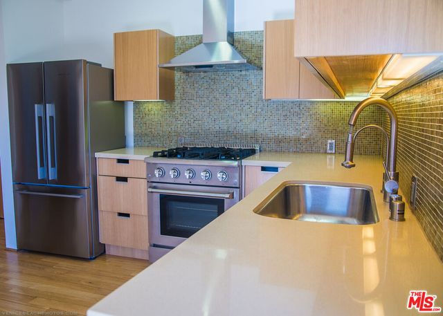 a kitchen with stainless steel appliances kitchen island a stove a sink and a refrigerator