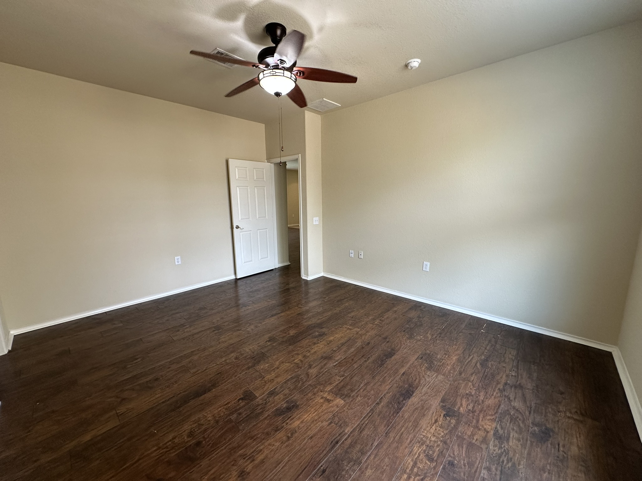 4507 Peach Grove Road Austin, TX 78744 - Photo 17 of 35 Rich wood flooring pairs beautifully with neutral walls in this versatile bedroom.