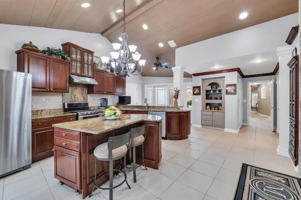 a kitchen with stainless steel appliances granite countertop a table chairs and a refrigerator