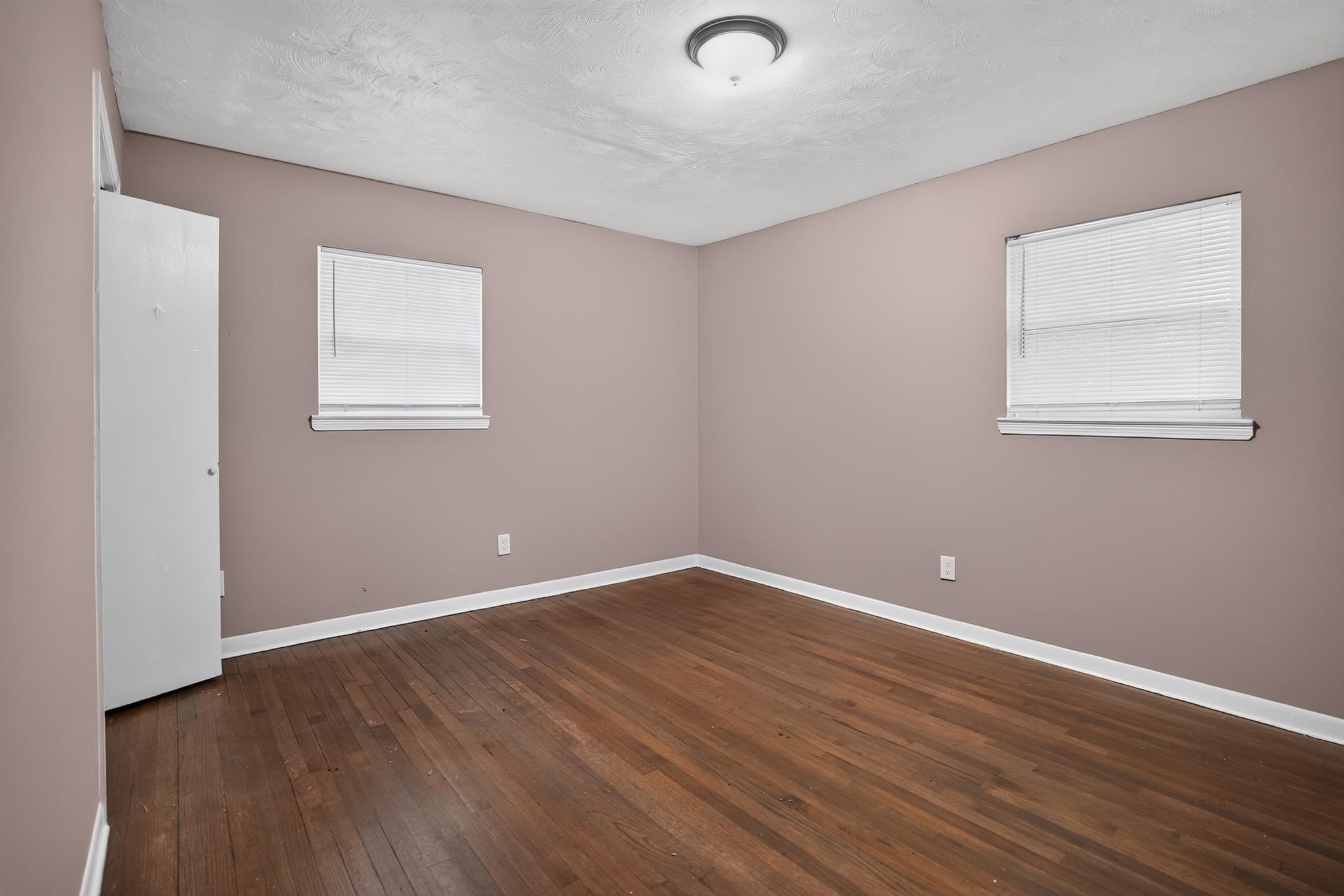 3391 South Perkins Road Memphis, TN 38118 - Photo 10 of 16 Spacious interior room featuring wood-finish flooring, two windows with blinds, a white door, white baseboards, and a ceiling-mounted light fixture