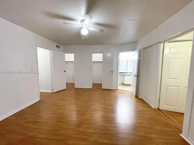 a view of an empty room with wooden floor and a window