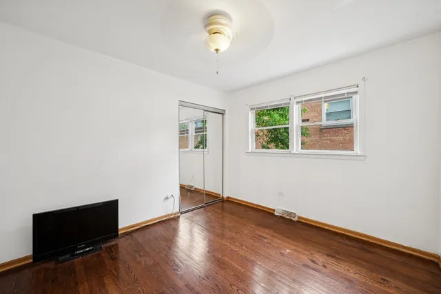 a view of empty room with wooden floor and fan