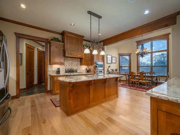 a large kitchen with stainless steel appliances granite countertop a lot of counter space and a wooden floor
