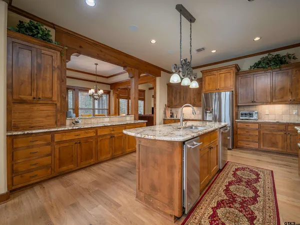 a large kitchen with stainless steel appliances granite countertop a stove and large wooden cabinets