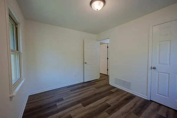 a view of an empty room with wooden floor and closet