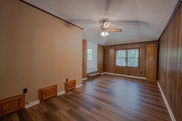 a view of an empty room with a window and wooden floor