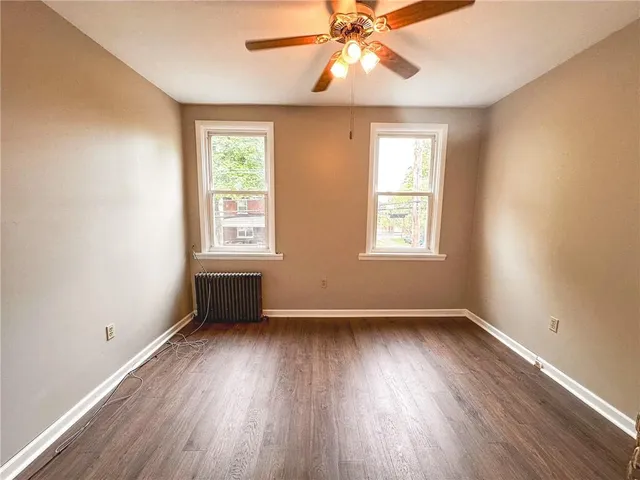 a view of an empty room with wooden floor and window