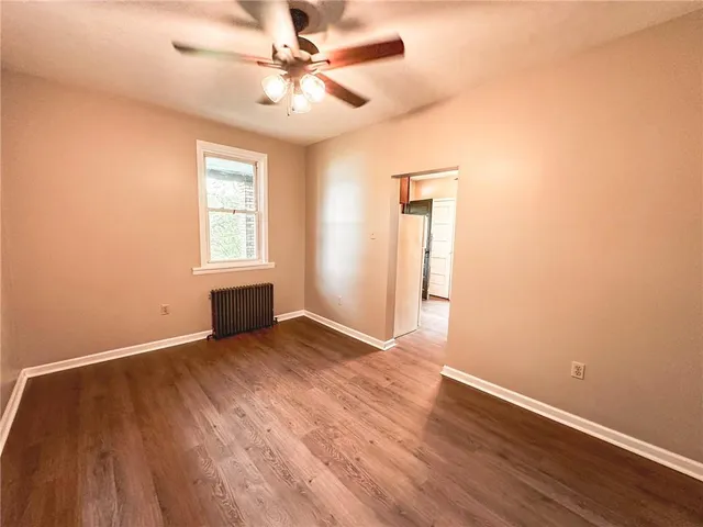 an empty room with wooden floor fan and windows