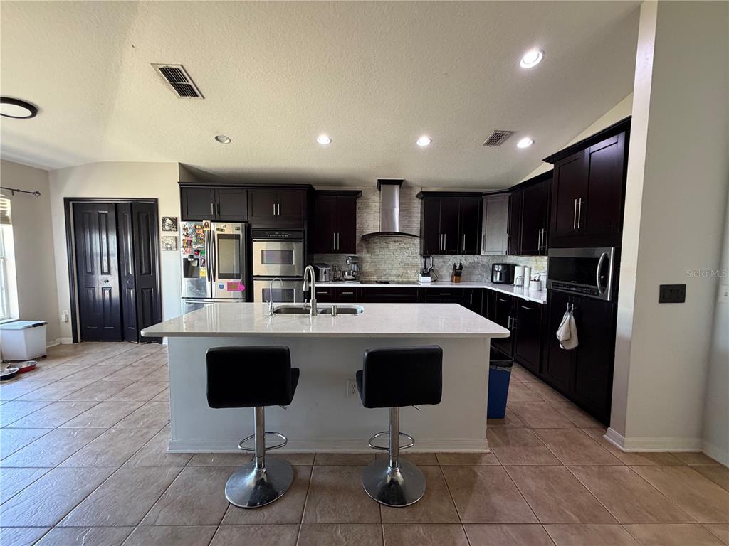 945 Tramells Trail Kissimmee, FL 34744 - Photo 12 of 36 a kitchen with kitchen island stainless steel appliances a sink a counter top space cabinets and a center island