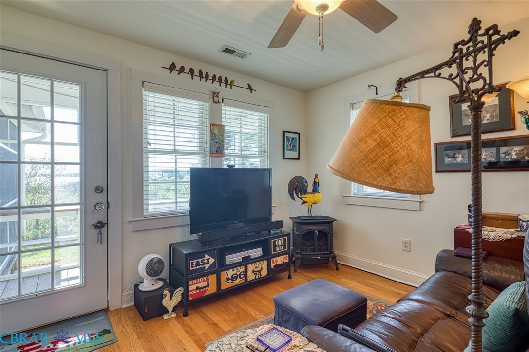 9078 Stump Point Road Hayes, VA 23072 - Photo 26 of 28 Living area featuring light wood-style flooring, a wood stove, and a ceiling fan