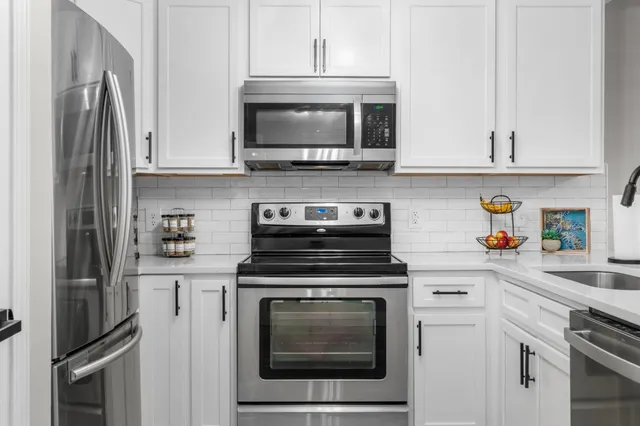 a kitchen with stainless steel appliances granite countertop a stove a refrigerator and a microwave