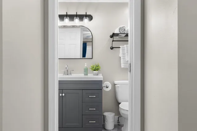 a bathroom with a granite countertop toilet sink and mirror