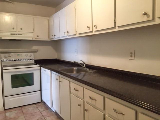 7913 Southwest 104th Street, Unit G207 Miami, FL 33156 - Photo 10 of 11 a kitchen with granite countertop white cabinets and a stove