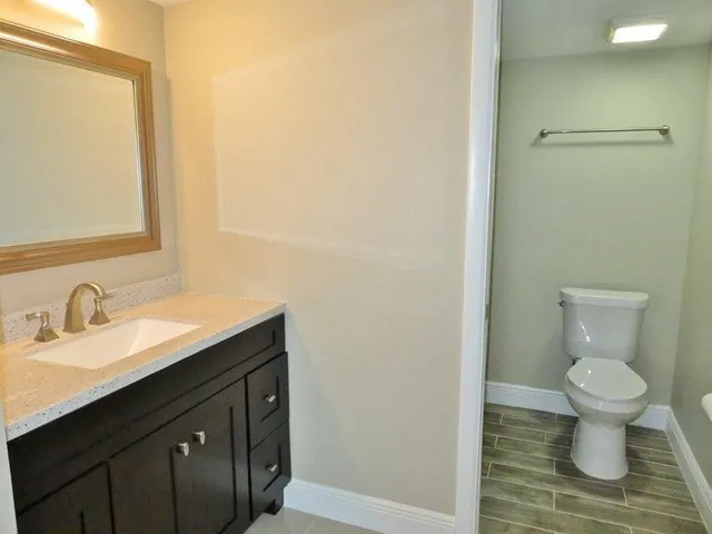 a bathroom with a granite countertop sink toilet and mirror