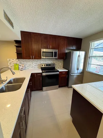 a kitchen with granite countertop a refrigerator stove and sink