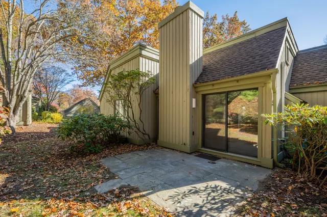 a view of a brick house with plants and large tree