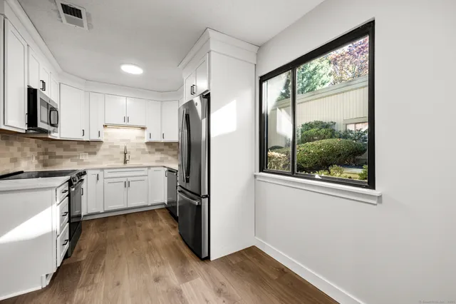 a kitchen with a refrigerator a stove top oven and a large window