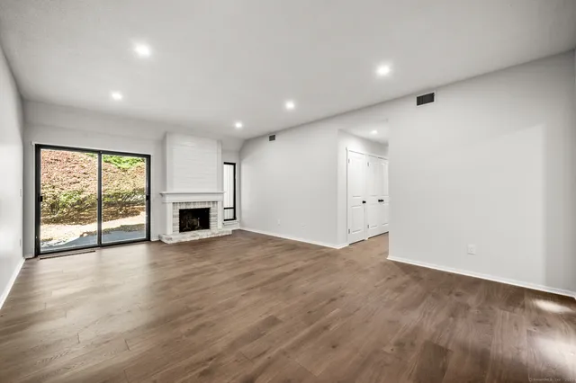 an empty room with wooden floor and fireplace