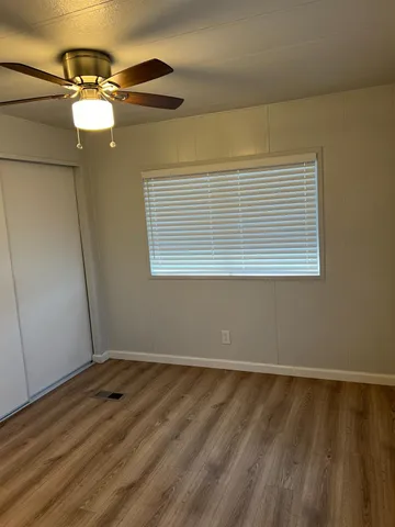 a view of an empty room with wooden floor and a window