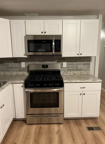 a kitchen with stainless steel appliances granite countertop a stove microwave and sink