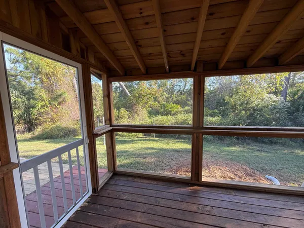 a view of a room with wooden floor next to a iron stairs